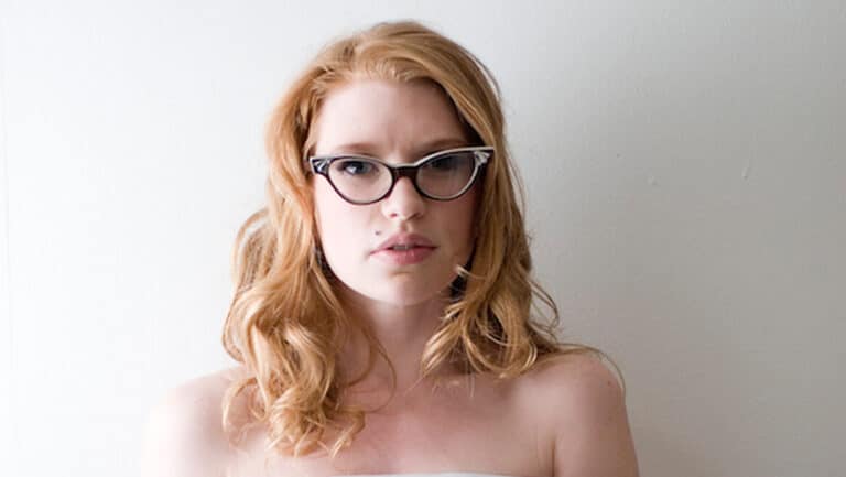 Portrait de Madison Young, cheveux roux ondulés et lunettes œil-de-chat